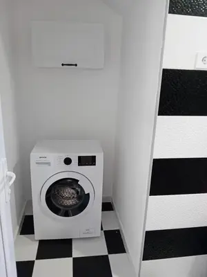 a washing machine in a bathroom with a checkered floor at Dara Apartmani in Donji Štoj