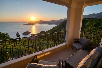 a balcony with a view of the ocean at sunset at Magic view - Apartment with Pool in Budva