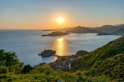 a view of a bay with the sun setting over the ocean at Magic view - Apartment with Pool in Budva