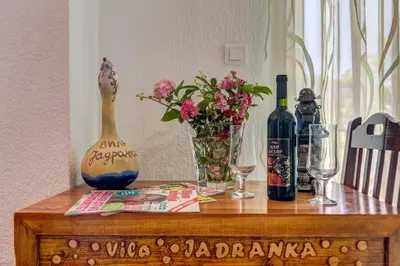 a wooden table with wine bottles and flowers on it at Villa Jadranka Sutomore in Sutomore