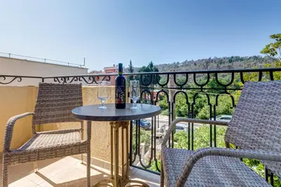 a table with two chairs and a bottle of wine on a balcony at Villa Jadranka Sutomore in Sutomore