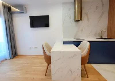 a kitchen with a counter and two chairs and a sink at Stylish Apartment with Elegant Touches in Podgorica