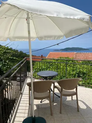 a table and chairs under an umbrella on a balcony at Mali apartman in Podličak