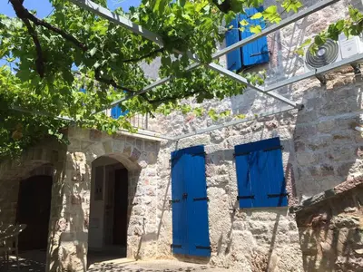 an old stone building with blue doors and windows at Mali apartman in Podličak