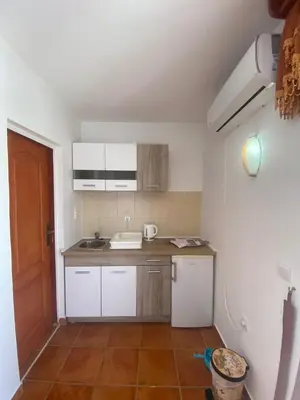a small kitchen with white cabinets and a sink at Mali apartman in Podličak