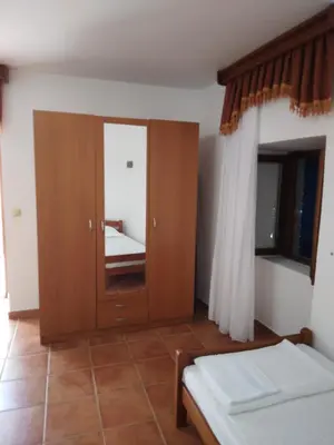 a bedroom with a wooden cabinet with a mirror at Mali apartman in Podličak