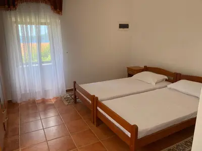 two beds in a room with a window at Mali apartman in Podličak