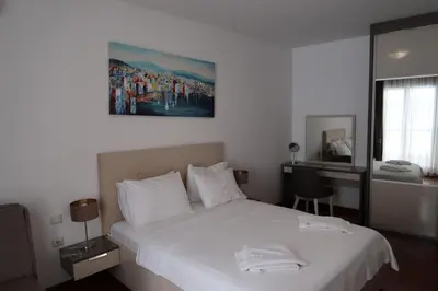 a bedroom with a large white bed and a desk at Apartmani LUX Becici in Becici