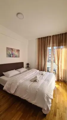 a bedroom with a large white bed in front of a window at Zoya Apartment in Podgorica