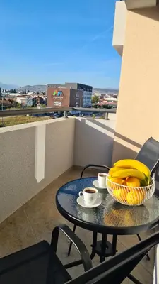 a table with a bowl of bananas and coffee on a balcony at Zoya Apartment in Podgorica