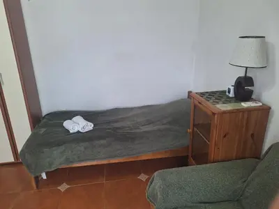 a bedroom with a bed with a lamp and a chair at Apartment at villa with pool in Budva