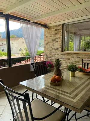 a dining table and chairs in a room with a balcony at Apartments Bajkovic in Kotor