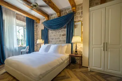 a bedroom with a large bed with blue curtains at Kerber-Graz 1860 in Kotor