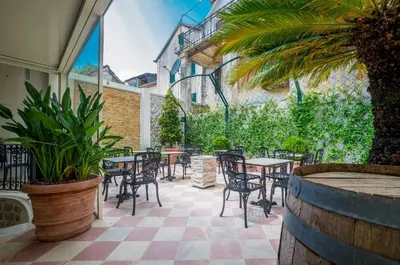 an outdoor patio with tables and chairs and plants at Kerber-Graz 1860 in Kotor