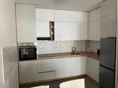 a kitchen with white cabinets and a black refrigerator at Apartman City Kvart Podgorica lux in Podgorica