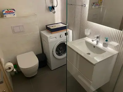 a small bathroom with a washing machine and a sink at Apartman City Kvart Podgorica lux in Podgorica