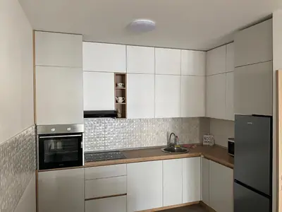 a kitchen with white cabinets and a black refrigerator at Apartman City Kvart Podgorica lux in Podgorica