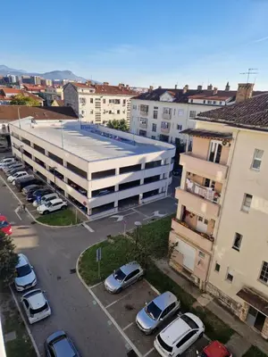 an apartment building with cars parked in a parking lot at Rosemary in Podgorica
