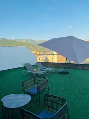 a table and chairs and an umbrella on a roof at Penthouse Victoria in Budva