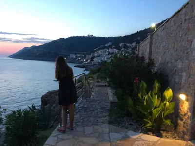 a woman standing on a wall looking at the water at Holiday Home Siesta in Dobra Voda