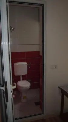 a bathroom with a toilet and a red wall at Marko Apartment in Sutomore