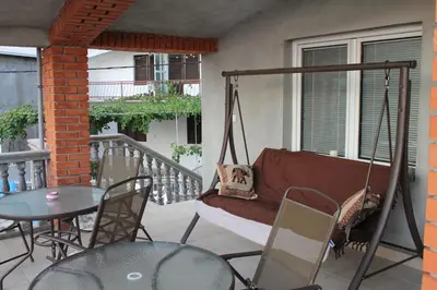 a porch with a swing and a table and chairs at Marko Apartment in Sutomore