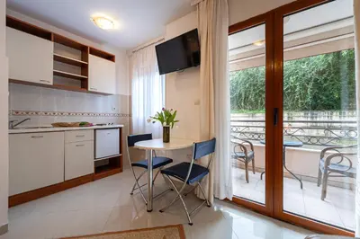 a kitchen with a table and chairs and a balcony at Maslina Residence in Budva