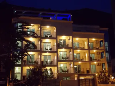 a tall building with lights on it at night at Apartments and Rooms Grand Palazzo in Budva
