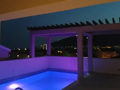 a swimming pool on the roof of a building at night at Apartments and Rooms Grand Palazzo in Budva