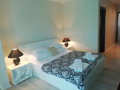 a bedroom with a large white bed with two lamps at Apartments and Rooms Grand Palazzo in Budva