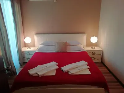 a bedroom with a red bed with two towels on it at Apartments and Rooms Grand Palazzo in Budva