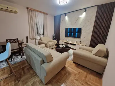 a living room with two couches and a flat screen tv at City Haven Deluxe in Podgorica