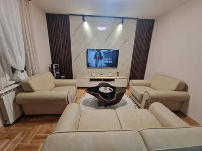 a living room with two couches and a flat screen tv at City Haven Deluxe in Podgorica