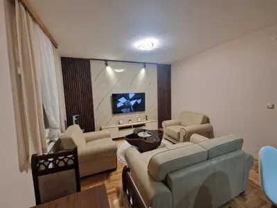 a living room with a couch and chairs and a tv at City Haven Deluxe in Podgorica