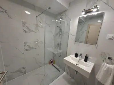 a bathroom with a shower and a sink and a mirror at Apartman Podgorica Vlado 1 in Podgorica