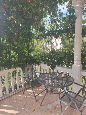 a table and chair on a porch next to a fence at Apartments at Villa with swimming pool&parking in Budva