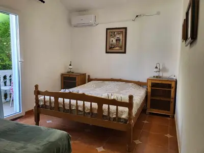 a bedroom with a bed and two tables and a window at Apartments at Villa with swimming pool&parking in Budva