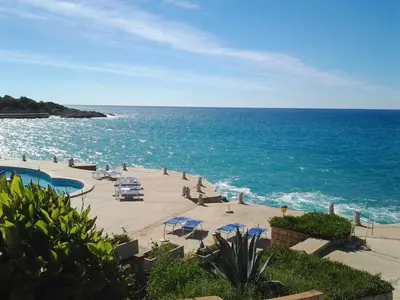 a beach with chairs and umbrellas and the ocean at Villa Rossa in Utjeha