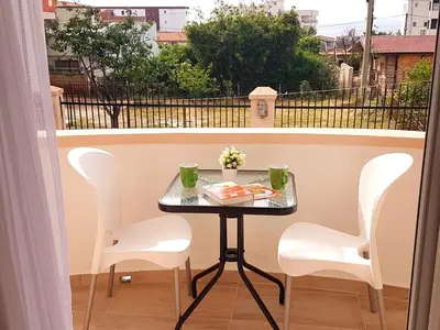 a small table on a balcony with white chairs at Apartments Taida in Dobra Voda