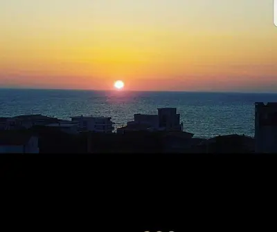 a sunset over the ocean with buildings in the foreground at Apartments Taida in Dobra Voda