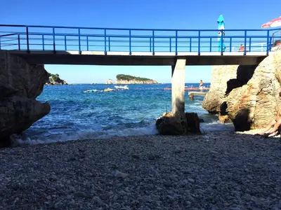 a bridge over the water with people on the beach at Apartment Cats in Utjeha