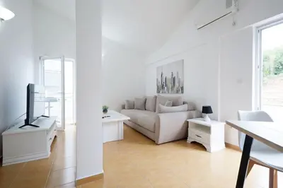 a white living room with a couch and a tv at Status-M Apartments Seoce 26 in Budva