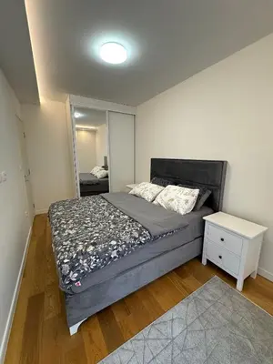 a bedroom with a large bed and a mirror at Stan AP Central Podgorica in Podgorica