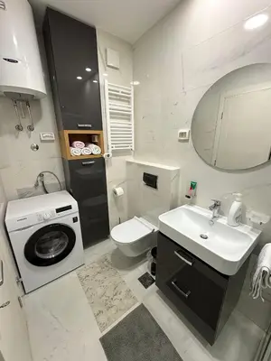 a bathroom with a toilet sink and a washing machine at Stan AP Central Podgorica in Podgorica