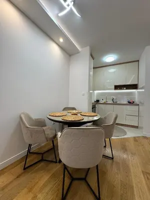 a dining room with a table and chairs and a kitchen at Stan AP Central Podgorica in Podgorica