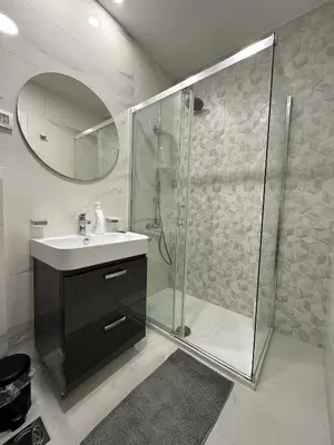 a bathroom with a shower and a sink and a mirror at Stan AP Central Podgorica in Podgorica