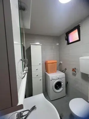a bathroom with a toilet and a washing machine at Studio apartman Gara in Kotor