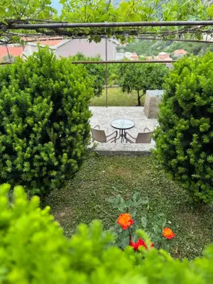 a patio with a table and chairs in a garden at Studio apartman Gara in Kotor
