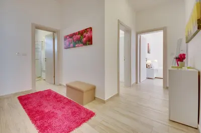 a living room with a pink rug and white walls at Sky Fort Apartment in Dobra Voda