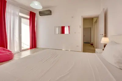 a bedroom with a large white bed with red curtains at Sky Fort Apartment in Dobra Voda
